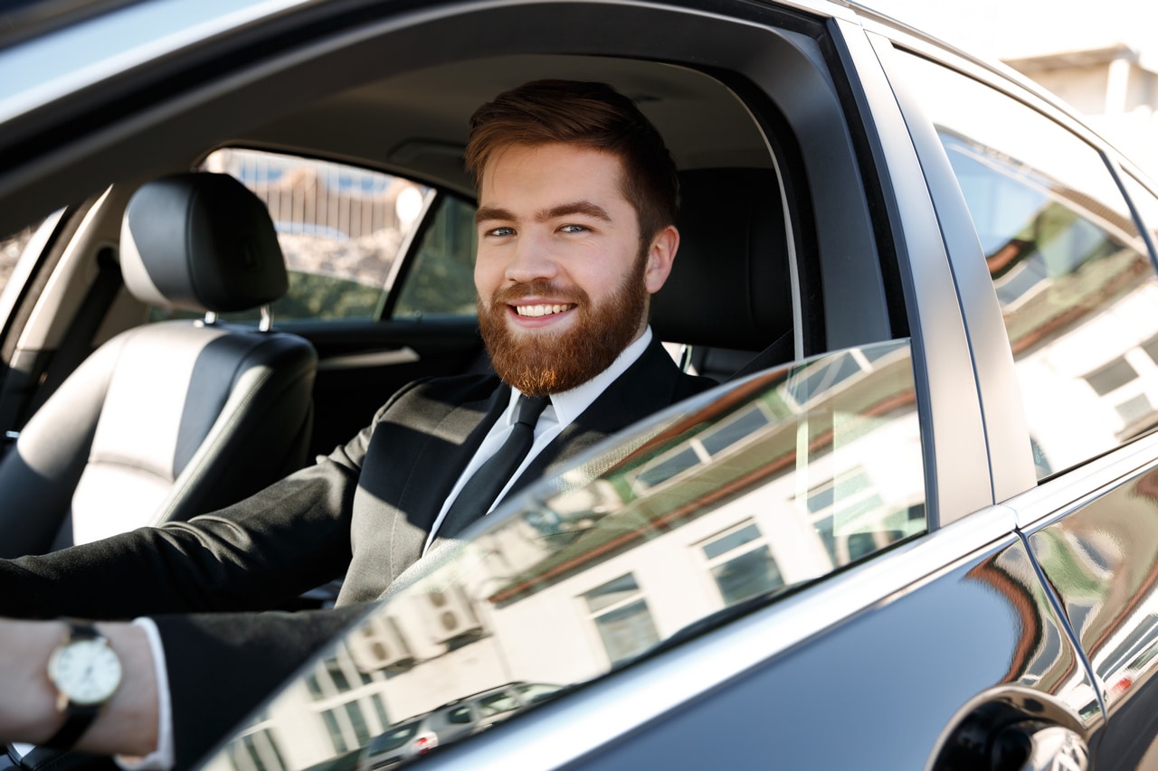 side-view-of-smiling-business-man-driving-car-PEV8CNV