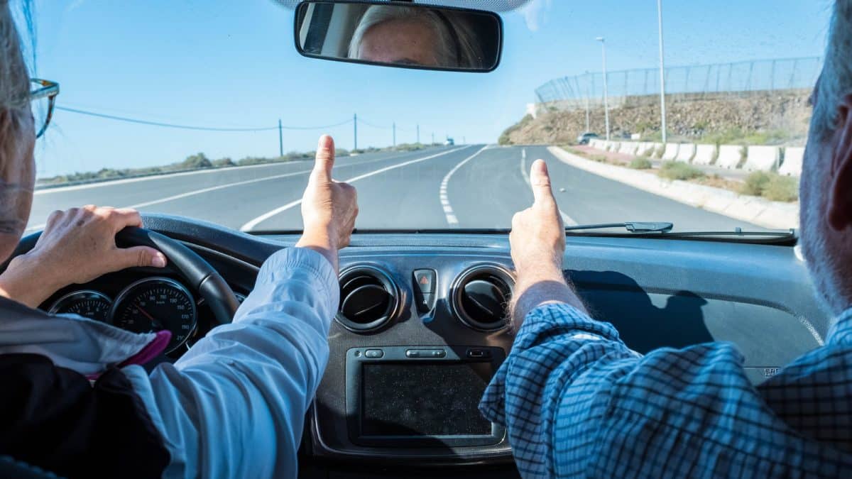 couple of seniors driving and having fun together with a rent car in the street - two pensioners